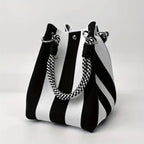 Black and white striped handbag with braided handles on a light gray background