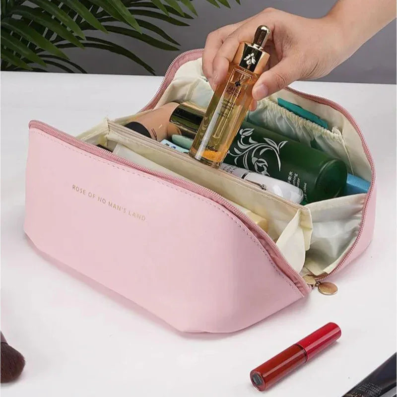 Pink cosmetic bag with various products on a white surface