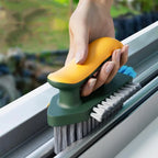 Hand using a window cleaning brush with a green handle and yellow scrubber on a window.