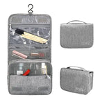 Gray fabric travel makeup bag shown open with compartments and included accessories, plus two smaller closed views on a white background.