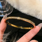Gold bracelet with diamonds held by a hand against a soft focus background