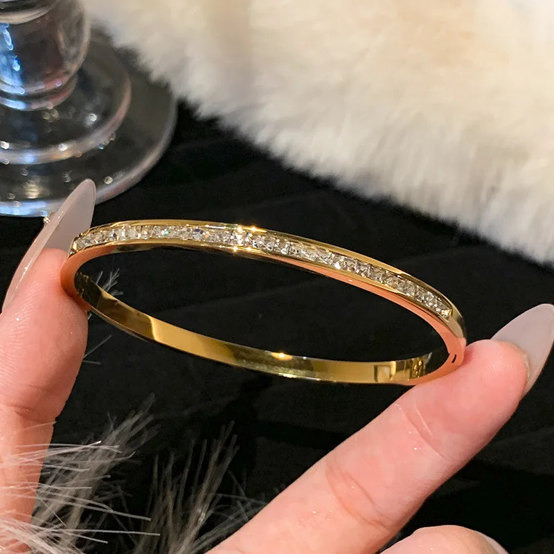 Gold bracelet with diamonds held by a hand against a soft focus background