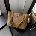 Brown handbag with gold chain strap on a dark surface