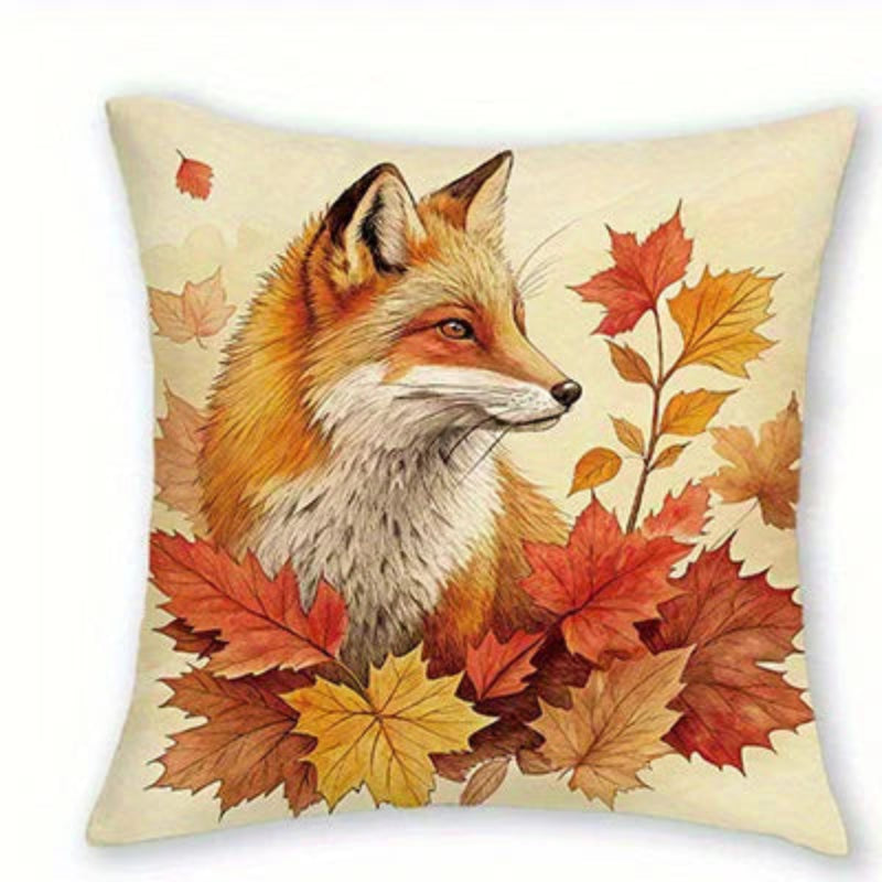 Square throw pillow featuring an artistic print of a fox surrounded by autumn maple leaves in shades of red, orange, yellow, and brown on a cream background.