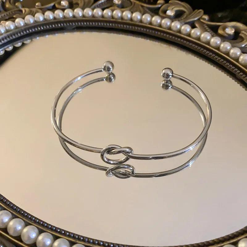 Silver bracelet with a knot design on a decorative mirror background