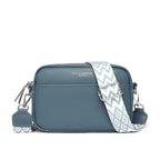 Blue leather crossbody bag with a patterned strap on a white background