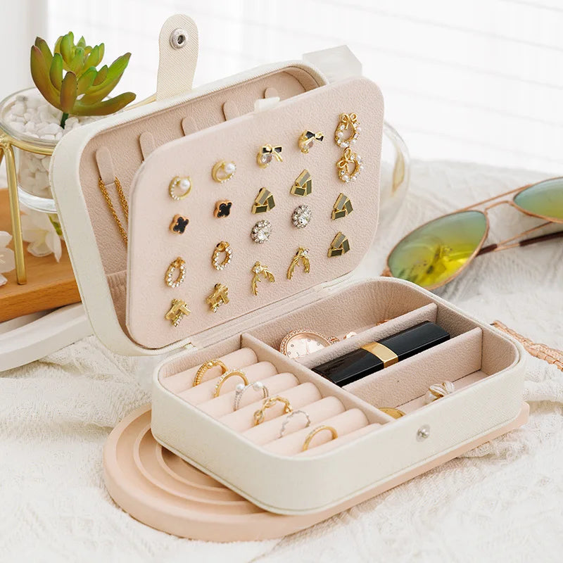 Beige jewelry case with earrings and rings on a light background