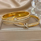 Gold bangles with diamond accents on a beige surface
