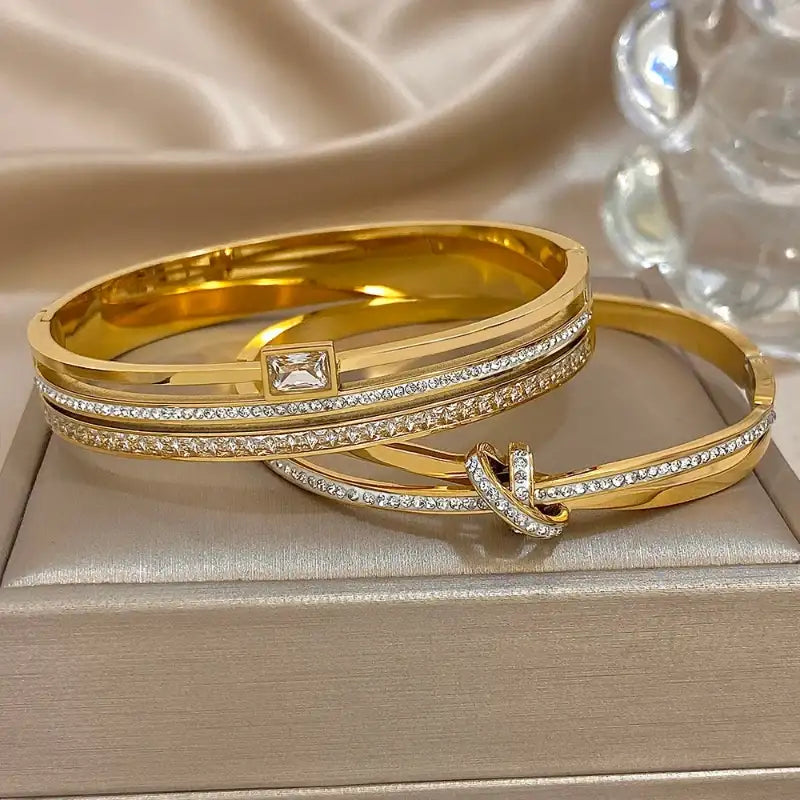 Gold bangles with diamond accents on a beige surface