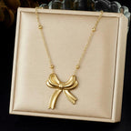 Gold bow-shaped necklace on a beige display box