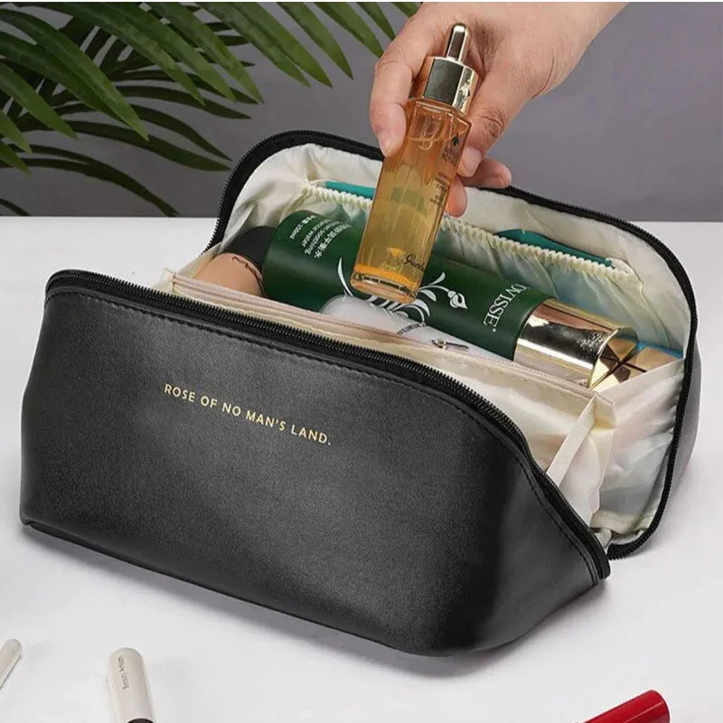 Black cosmetic bag with products and a hand holding a bottle of perfume.